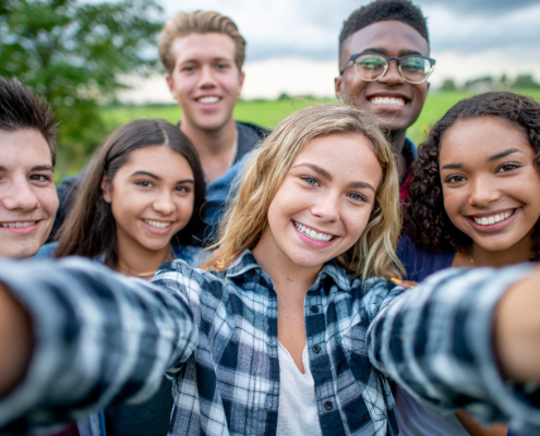 A group of multi-ethnic students taking a selfie outside. They are dressed casually and having fun together in a group.